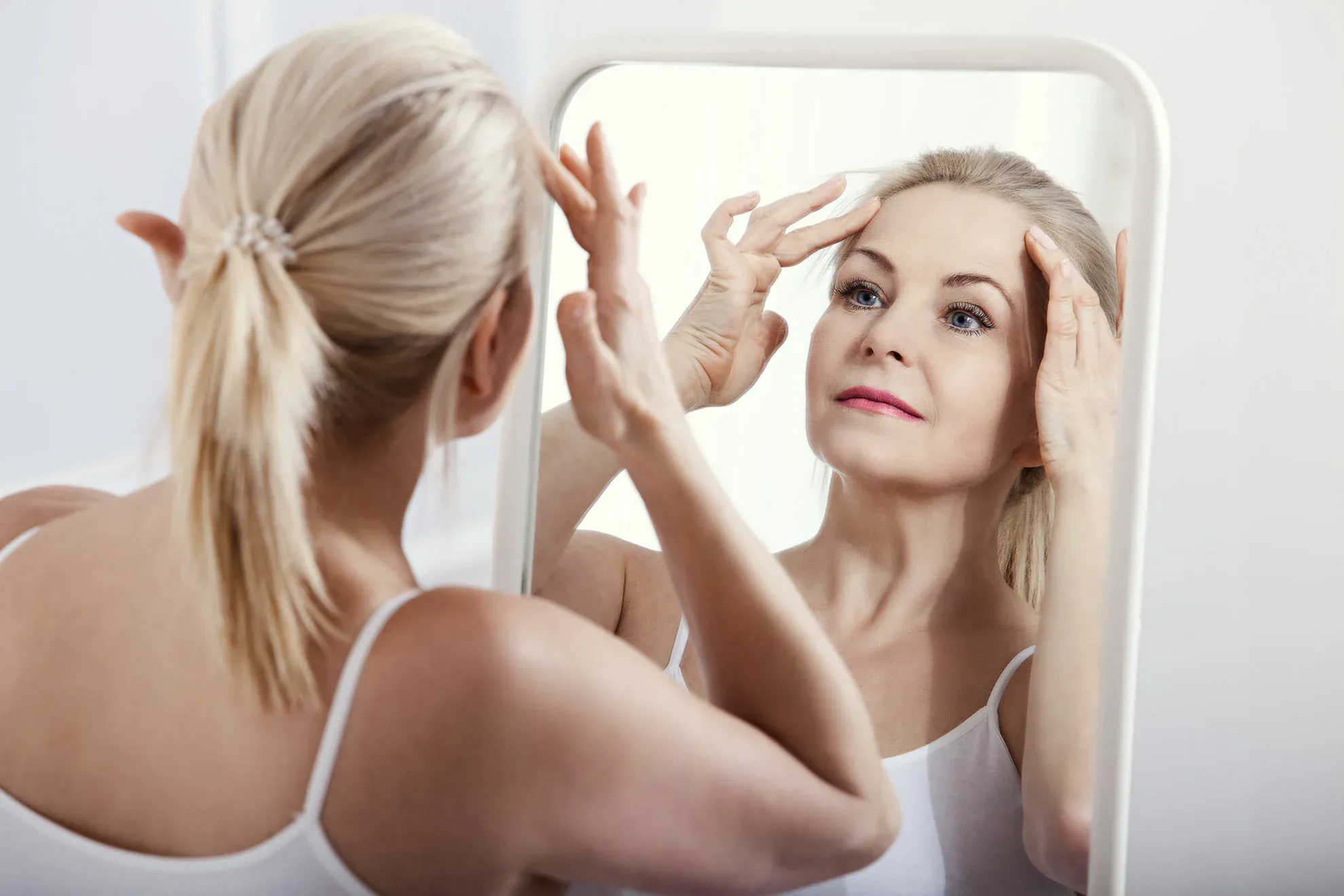 Woman checking skin in mirror confidently.